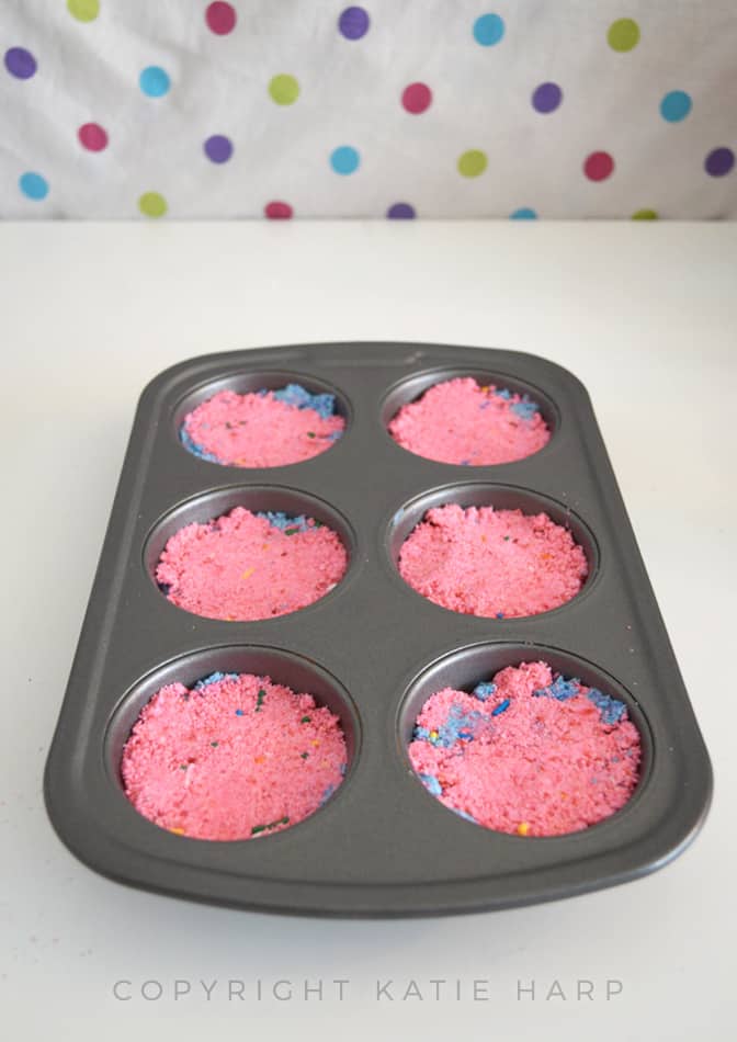 Putting more of the bath bomb mixture into a muffin tin