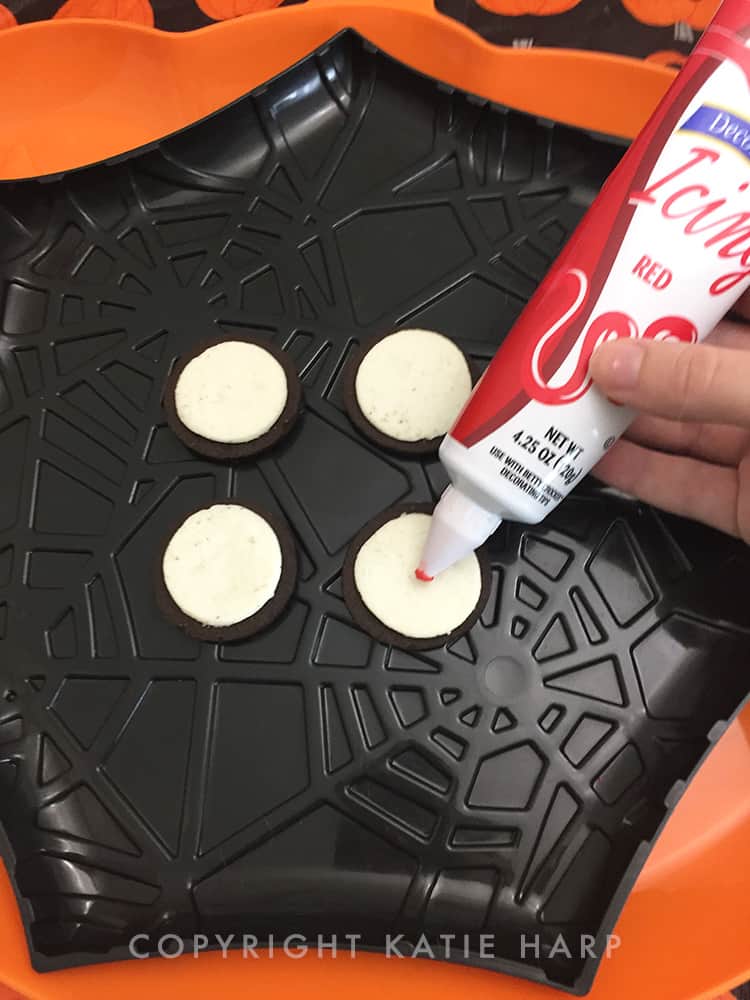 Adding red icing to the Oreo slices