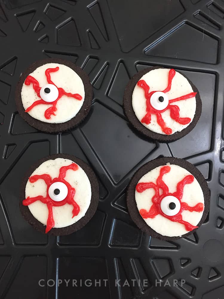 Adding candy eyeballs onto the bloody icing lines