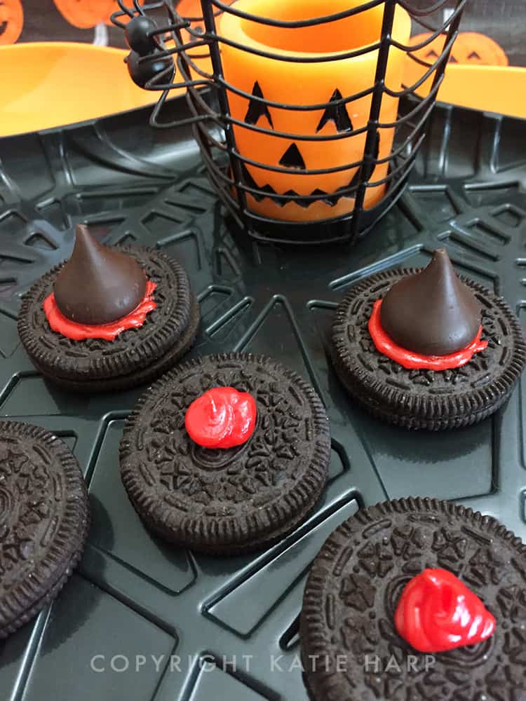 Attaching dark chocolate kisses to the red icing on the Oreos