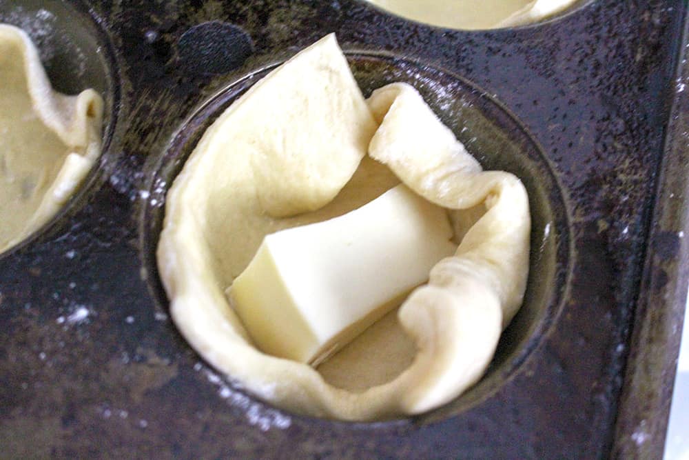 Putting the dough and cheese into a muffin tin