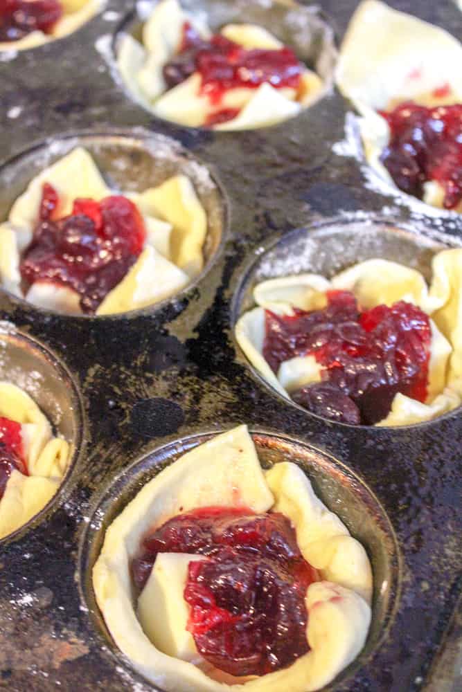 Adding cranberry sauce to the muffin tins